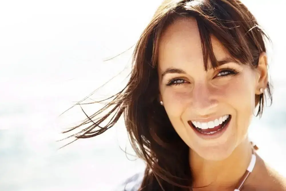 Woman smiling outdoors with bright, healthy teeth displaying cosmetic dentistry results.