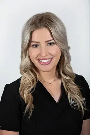 Maggie, dental professional at Las Vegas practice, smiling in black scrubs.