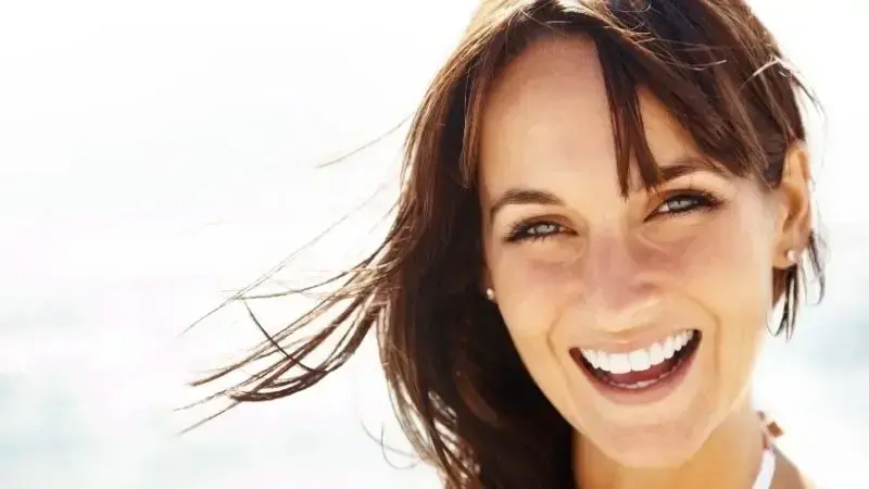 Smiling woman with bright white teeth after professional tooth whitening treatment.