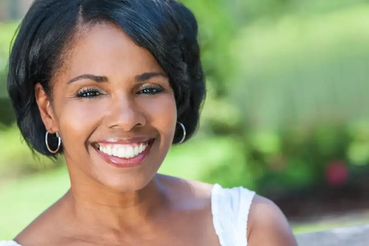 Woman smiling outdoors, displaying healthy teeth after root canal treatment.