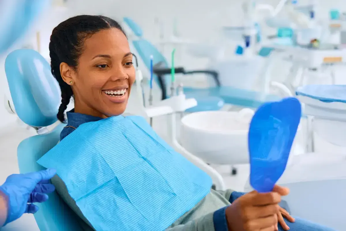 Happy patient in dental chair admiring her smile after same-day crown treatment.
