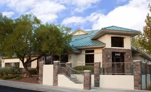 Exterior of dental practice at 3450 S Hualapai Way, Las Vegas, featuring brick facade and turquoise metal roof.