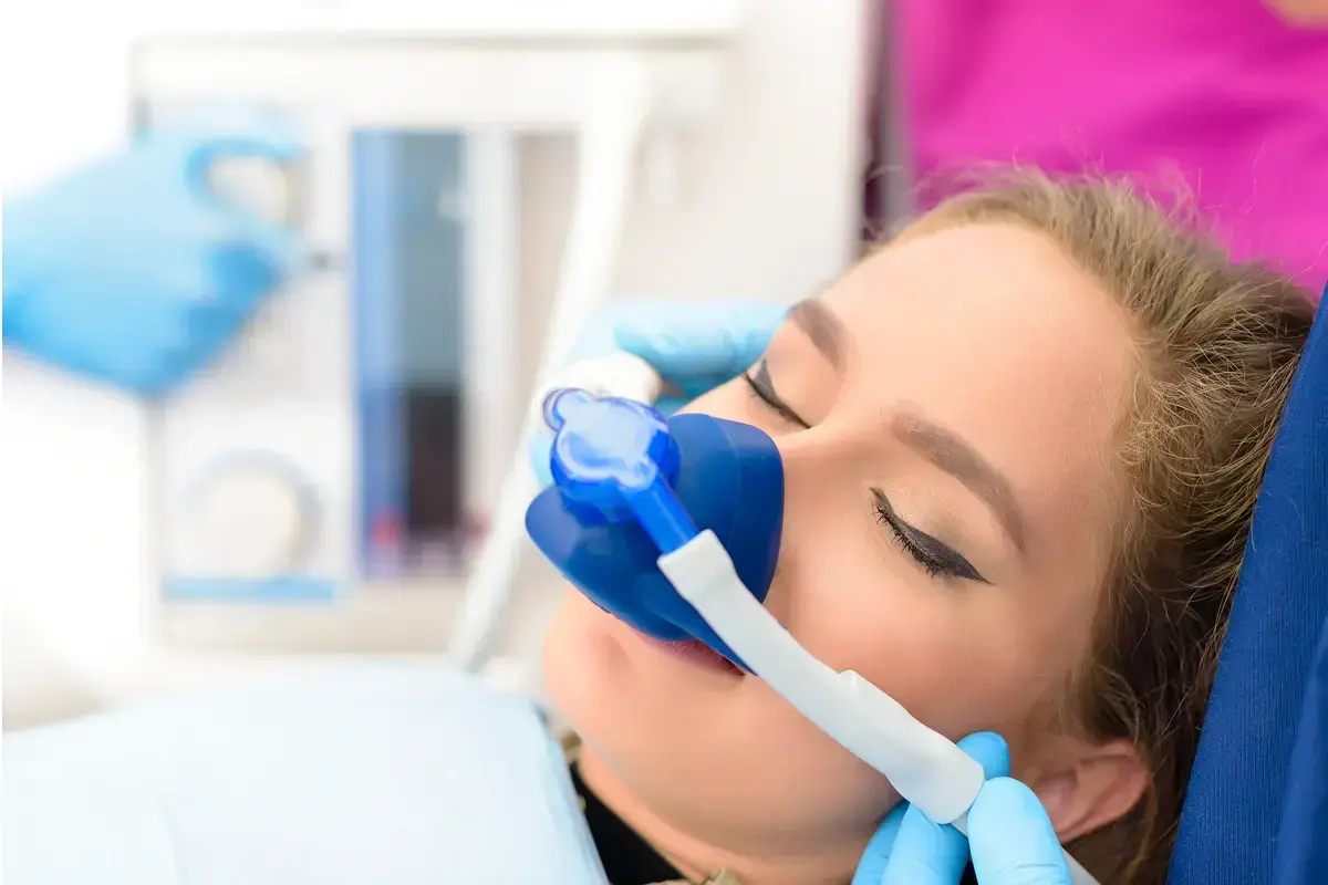 Patient using a blue dental inhaler or aerosol medication device during anxiety management treatment.